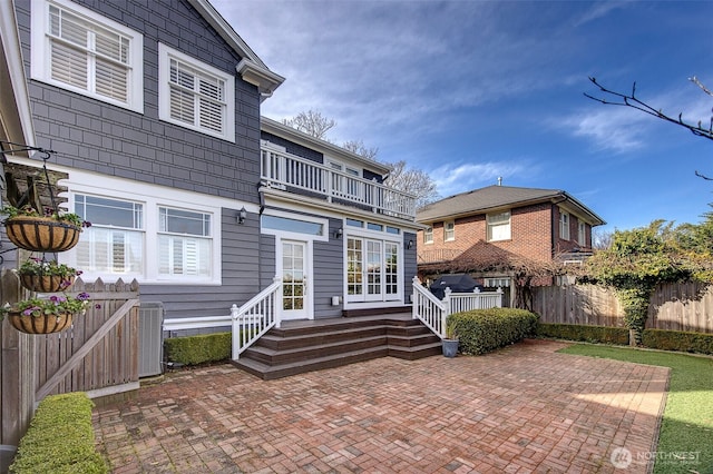 rear view of house featuring a balcony, cooling unit, a patio area, and fence