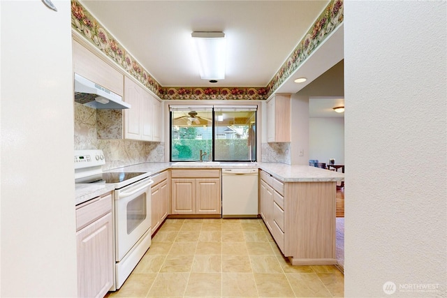 kitchen featuring white appliances, tasteful backsplash, a peninsula, light countertops, and under cabinet range hood