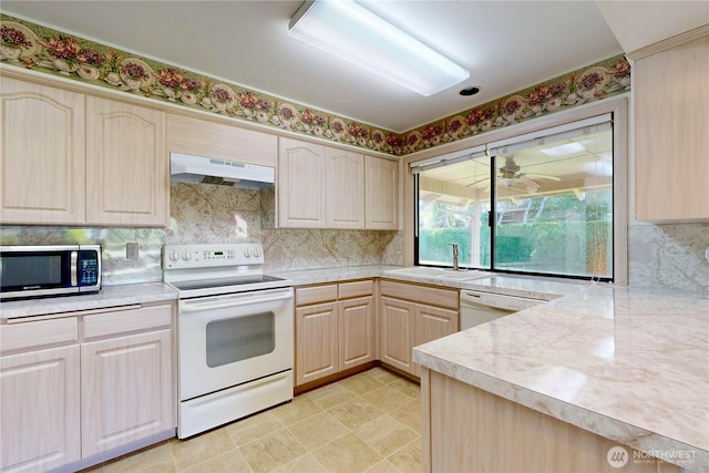 kitchen with white appliances, light countertops, under cabinet range hood, light brown cabinets, and a sink