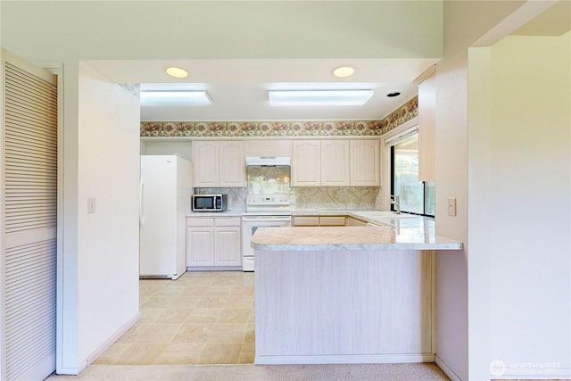 kitchen with white appliances, decorative backsplash, a peninsula, light countertops, and under cabinet range hood