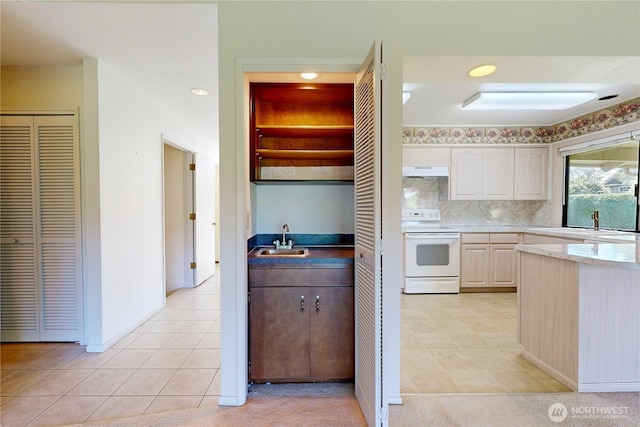 kitchen featuring backsplash, a sink, under cabinet range hood, and white electric range oven