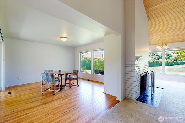 dining room with a chandelier, visible vents, baseboards, light wood-type flooring, and a brick fireplace