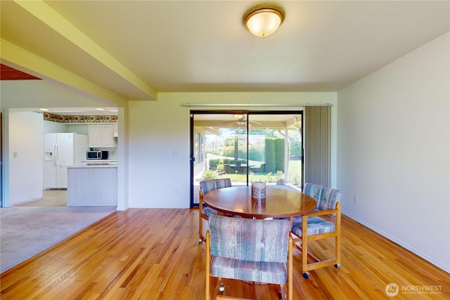 dining space featuring light wood-type flooring and baseboards