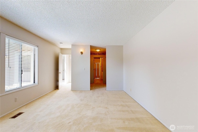 unfurnished room featuring light colored carpet, visible vents, and a textured ceiling