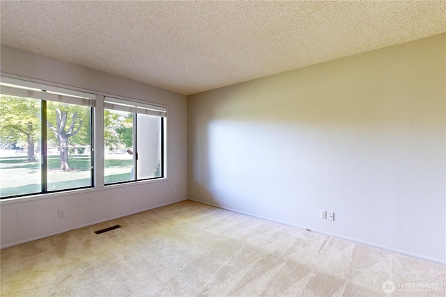 spare room with carpet, visible vents, and a textured ceiling