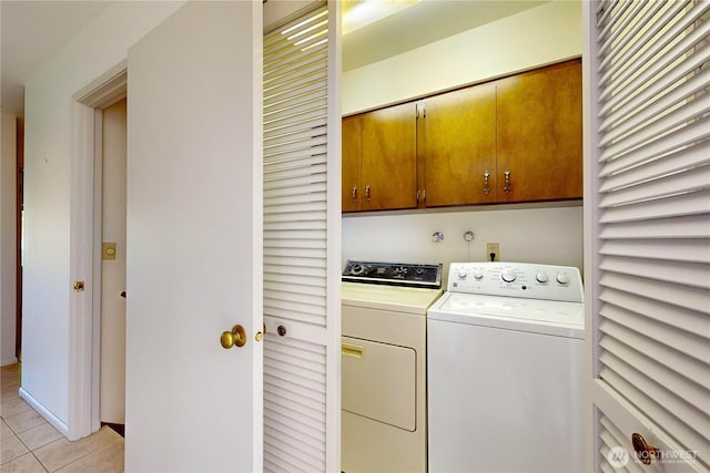 washroom with light tile patterned flooring, washing machine and dryer, and cabinet space