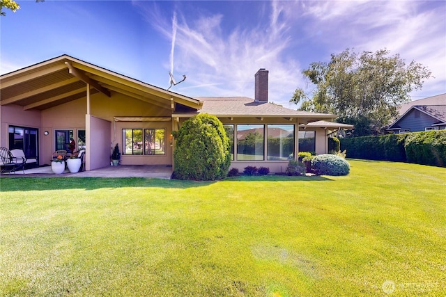 back of property featuring a yard, a chimney, stucco siding, a patio area, and fence