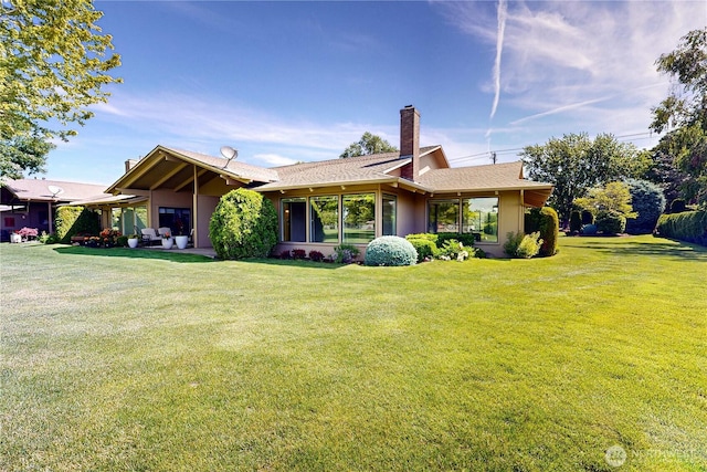 view of front of house featuring a front yard, a chimney, and stucco siding