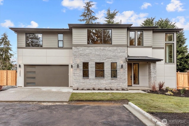 modern home with driveway, stone siding, an attached garage, fence, and a front yard