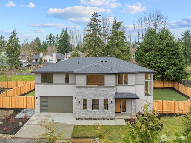 view of front of home with a garage, fence private yard, stone siding, driveway, and a front lawn