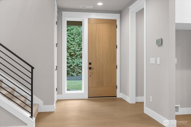 entryway with light wood finished floors, stairs, and baseboards