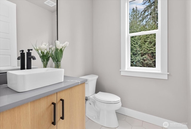 bathroom with toilet, visible vents, vanity, baseboards, and tile patterned floors