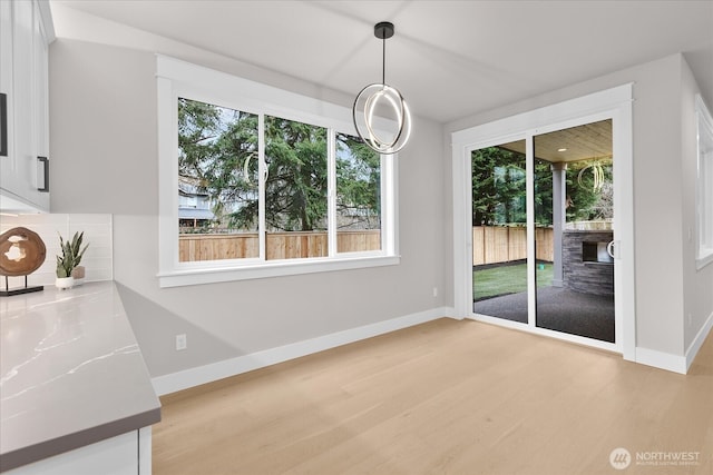 unfurnished dining area with light wood-style flooring and baseboards