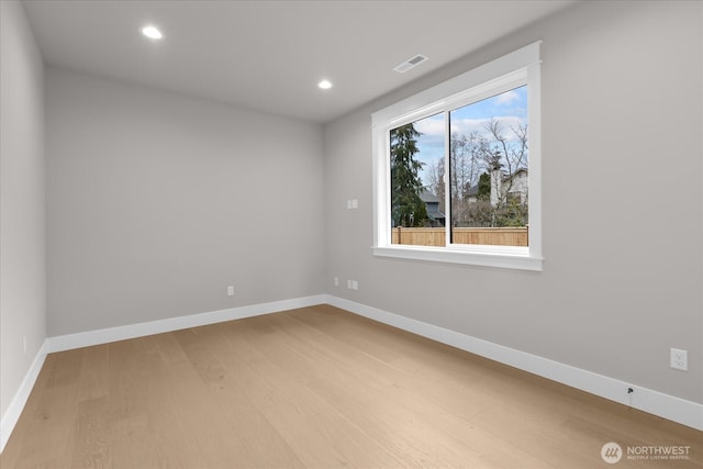 spare room with visible vents, baseboards, and wood finished floors