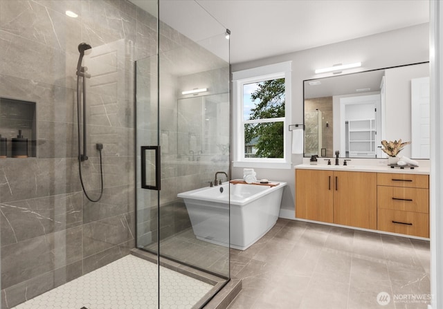 full bathroom featuring a stall shower, a freestanding bath, and vanity