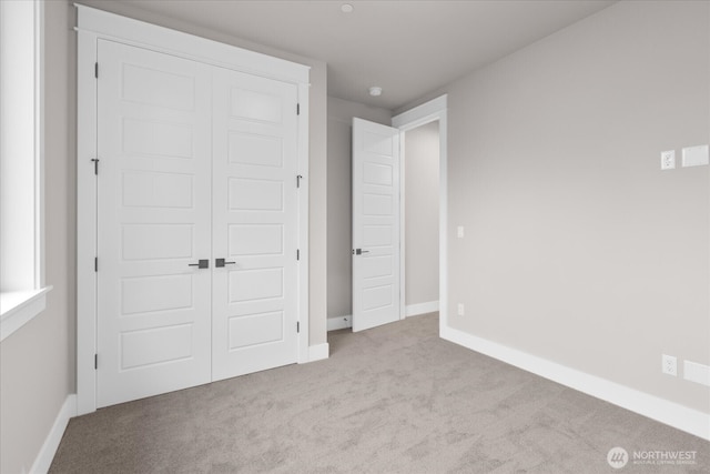 unfurnished bedroom with a closet, carpet flooring, and baseboards