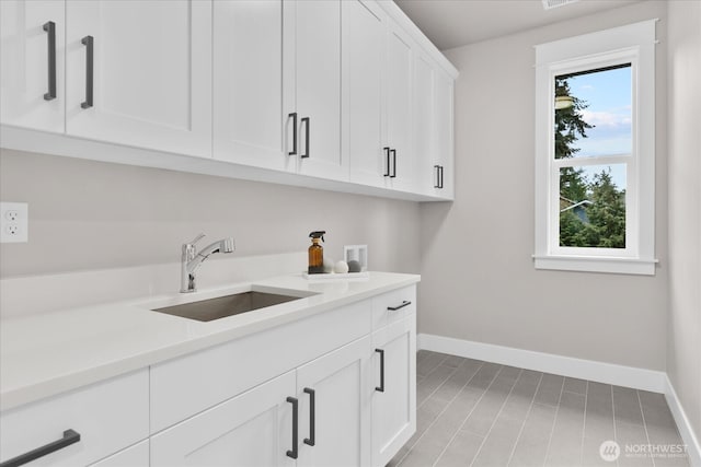 laundry room with cabinet space, baseboards, washer hookup, and a sink