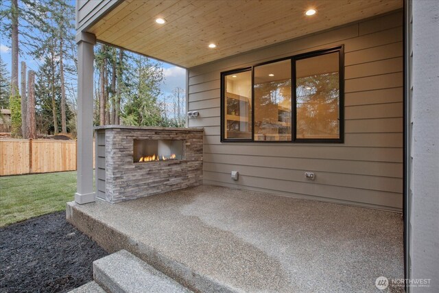 view of patio / terrace with a lit fireplace and fence