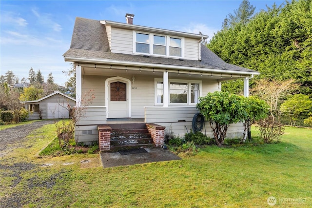 bungalow-style home featuring an outbuilding, driveway, a shingled roof, and a front yard