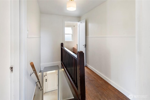 staircase with wood finished floors and wainscoting