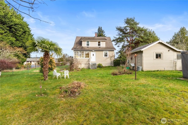 back of house featuring entry steps, a chimney, and a yard