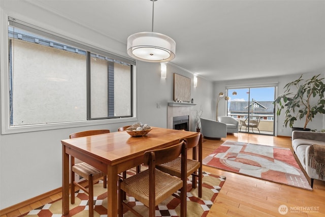 dining area featuring ornamental molding, wood finished floors, a tile fireplace, and baseboards