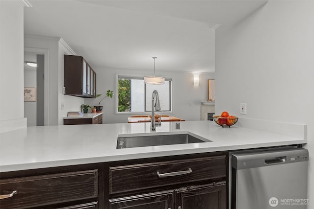 kitchen featuring light countertops, stainless steel dishwasher, a sink, and dark brown cabinetry