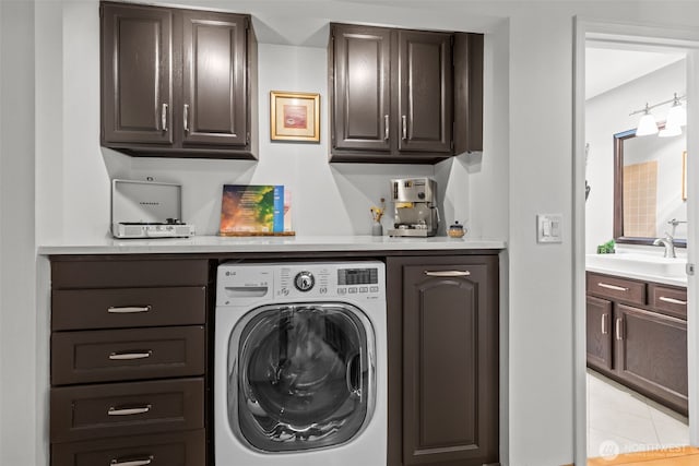 clothes washing area with light tile patterned flooring, cabinet space, a sink, and washer / dryer