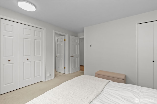 bedroom with multiple closets and carpet flooring