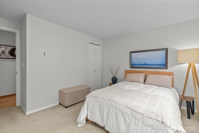 bedroom with a closet, light colored carpet, and baseboards