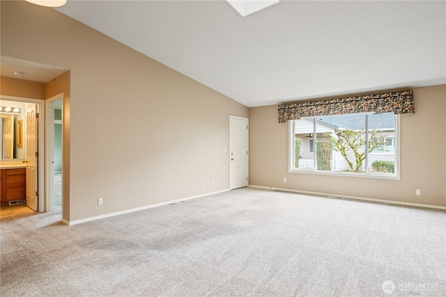 spare room with lofted ceiling, baseboards, and light colored carpet