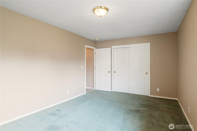 unfurnished bedroom with carpet, a closet, a textured ceiling, and baseboards