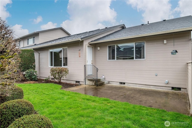 back of property with a shingled roof, a yard, and a patio