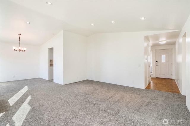 carpeted spare room with a chandelier, recessed lighting, and vaulted ceiling