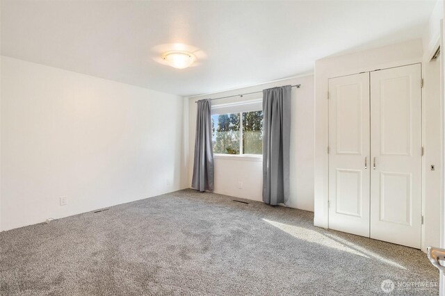 unfurnished bedroom with carpet floors, visible vents, and a closet