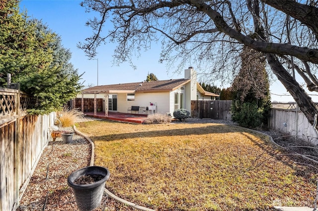 rear view of property featuring a yard, a chimney, and a fenced backyard