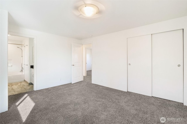 unfurnished bedroom with ensuite bathroom, a closet, and carpet