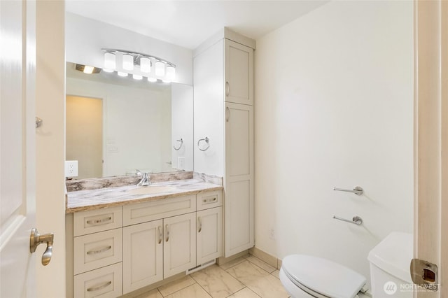 bathroom featuring marble finish floor, baseboards, vanity, and toilet