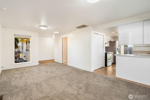 spare room featuring light colored carpet and visible vents