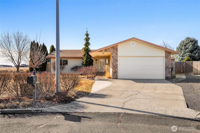 ranch-style house featuring a garage, stone siding, concrete driveway, and fence