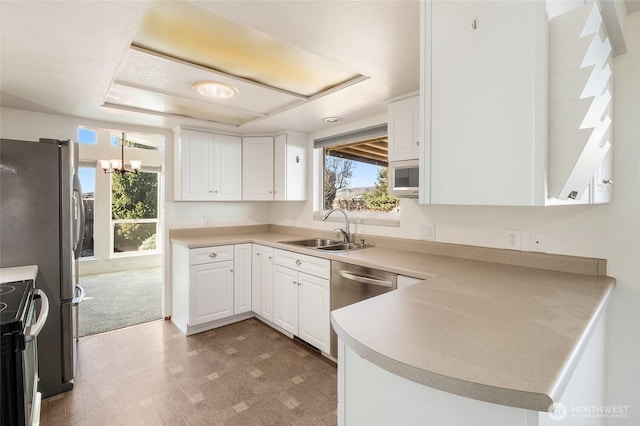 kitchen with a peninsula, electric range, white cabinetry, and a sink