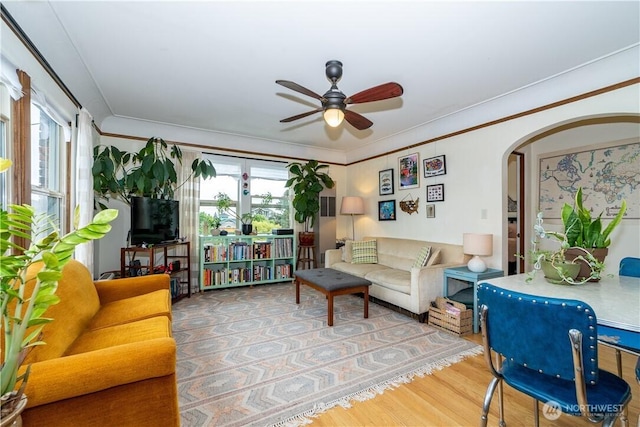 living room featuring ornamental molding, arched walkways, a healthy amount of sunlight, and wood finished floors