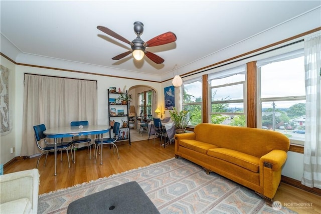 living area featuring crown molding, arched walkways, a wealth of natural light, and wood finished floors