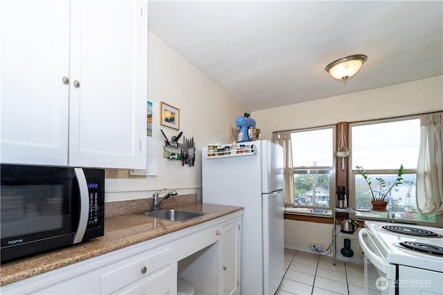 kitchen with light tile patterned floors, light stone counters, white appliances, a sink, and white cabinets