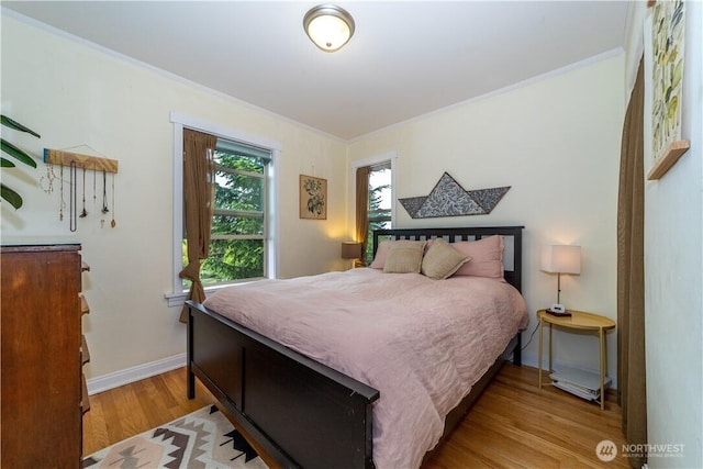 bedroom featuring light wood-style floors, baseboards, and crown molding