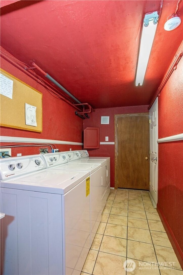 laundry room featuring light tile patterned floors, laundry area, washing machine and dryer, and visible vents