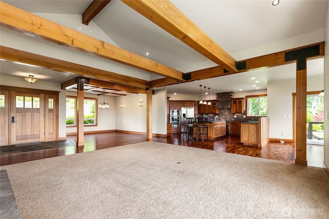 unfurnished living room with plenty of natural light, baseboards, and beamed ceiling