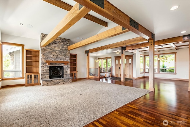 unfurnished living room featuring vaulted ceiling with beams, a stone fireplace, baseboards, and wood finished floors