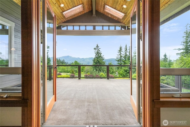 entryway with lofted ceiling with skylight, carpet flooring, a mountain view, and a healthy amount of sunlight