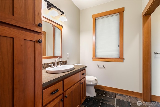 bathroom with baseboards, vanity, and toilet